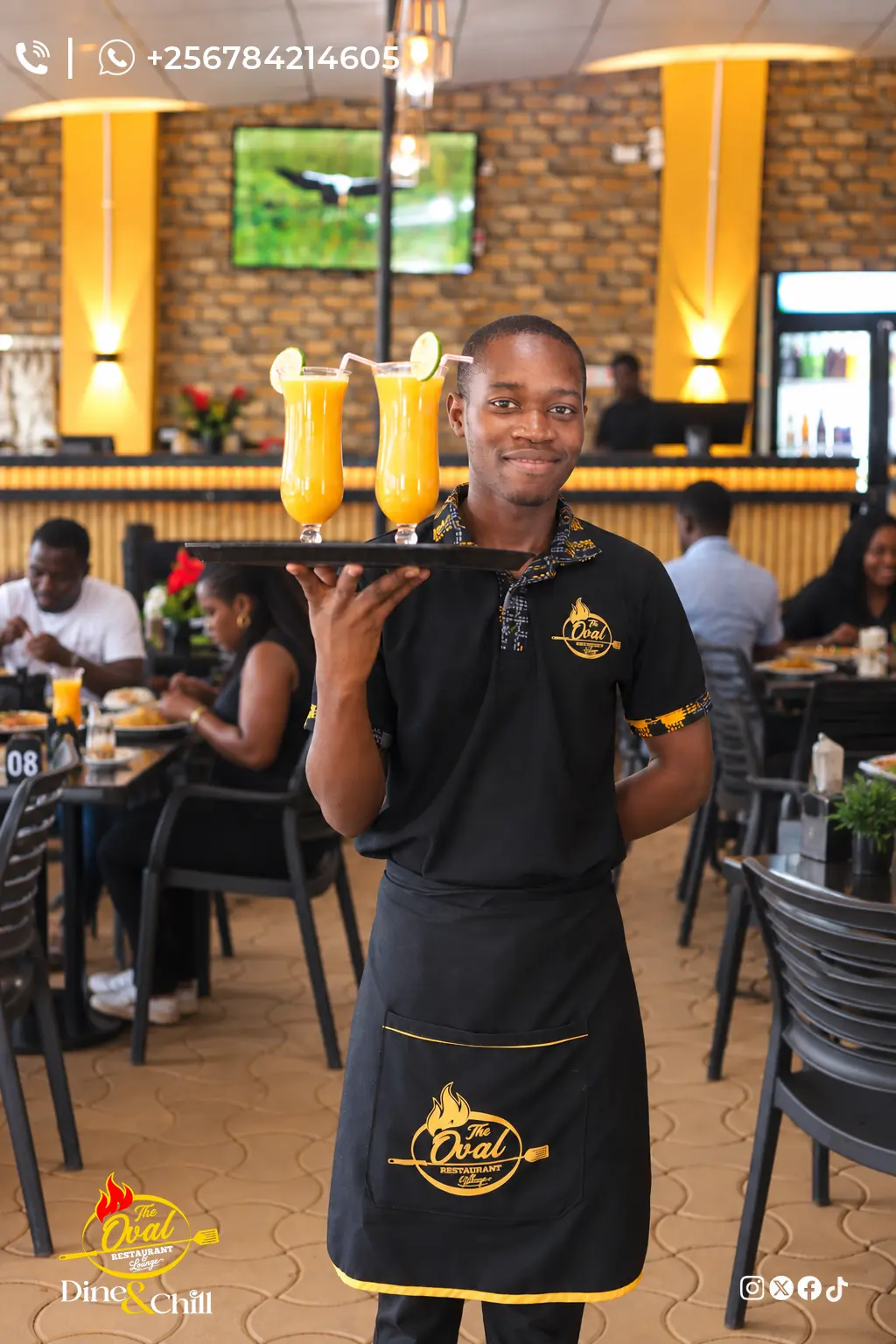 Oval waiter carrying a tray of two tall fresh mango juices through the dining room