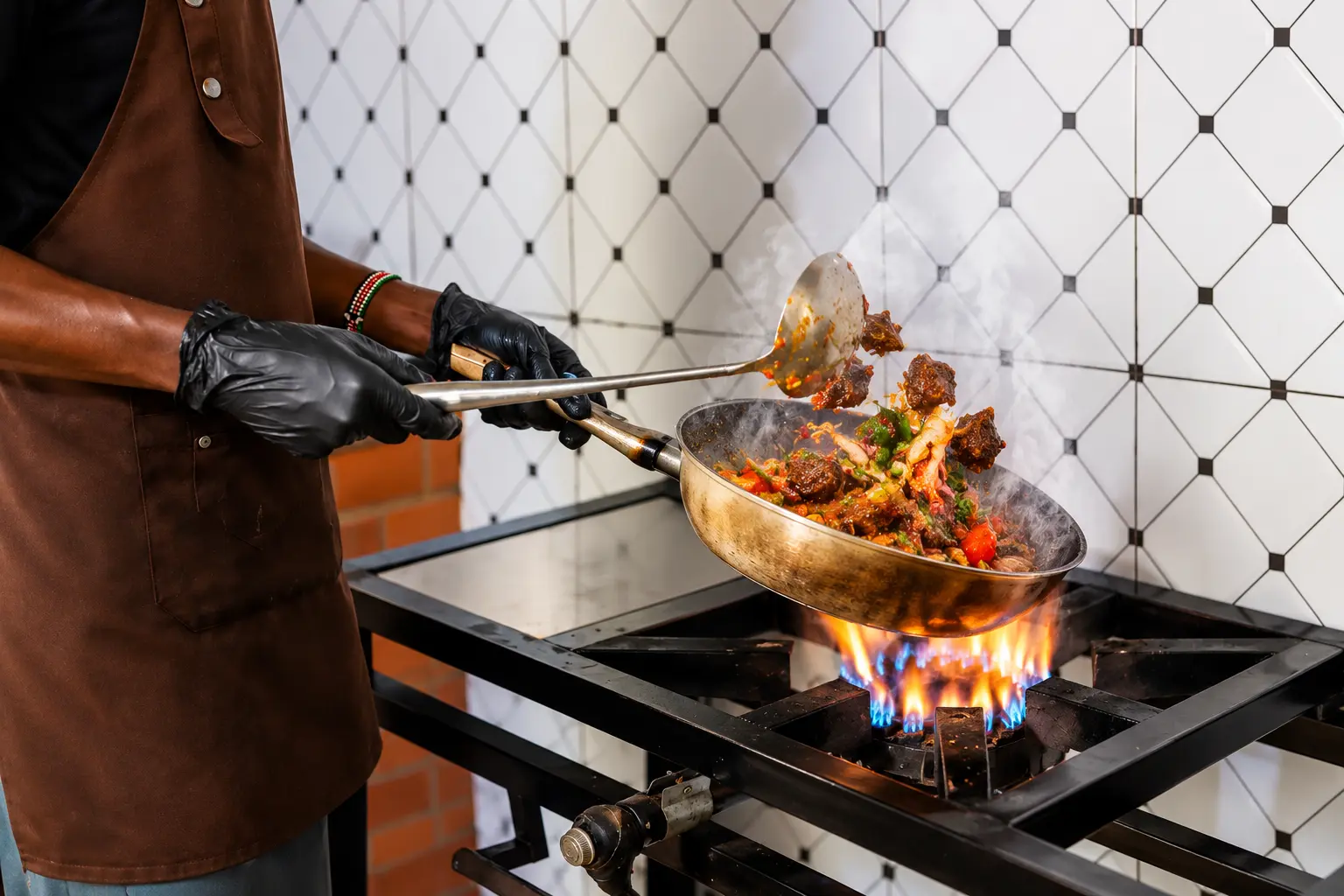 Oval cook tossing spiced meat in a pan over an open gas flame